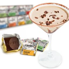 a glass filled with ice cream sitting next to some chocolates and candy bar wrappers