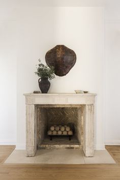 a white fireplace with a potted plant on top