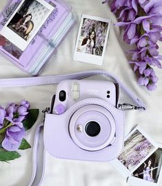 a purple camera sitting on top of a white bed next to flowers and pictures with polaroid frames