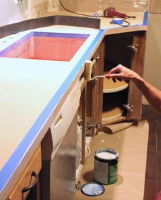 a man is painting the counter top with blue paint and white primer on it