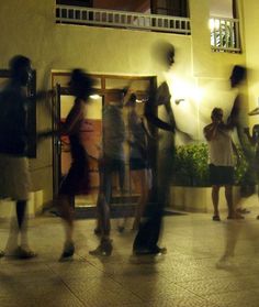 blurry photograph of people standing in front of a building with their arms around each other