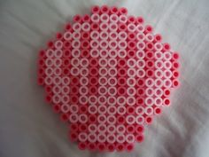 a red and white object made out of plastic beads on a bed with the cover pulled down