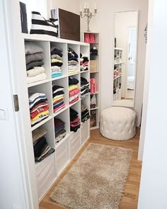 a white closet filled with lots of different types of clothes and rugs on the floor