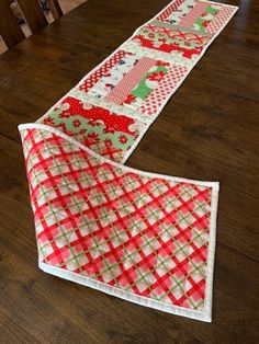 two red and green quilted table runners sitting on top of a wooden floor