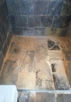 a tiled shower stall in a bathroom with stone flooring