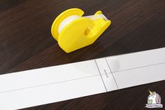 a yellow stapler sitting on top of a wooden table next to a white piece of paper