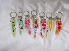 six different key chains with beads and letters on them, all hanging from the same metal ring