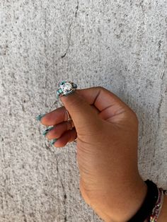 a woman's hand with two rings on top of her finger, against a wall