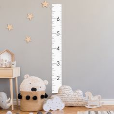 a child's room with a growth chart and teddy bear toys on the floor