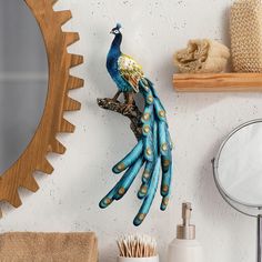 a peacock figurine sitting on top of a wooden branch next to a mirror