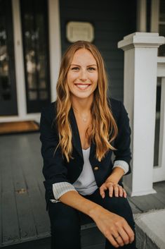 a smiling woman sitting on the front steps of a house