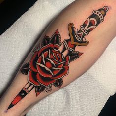 a rose and dagger tattoo on the arm