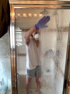 a man standing in front of a shower with his hands on the head and arms behind him