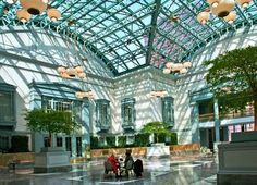 people are sitting at a table in the middle of a large building with a glass roof