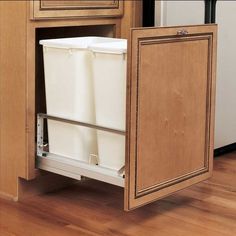 a kitchen cabinet with two white buckets in the bottom drawer and an open door