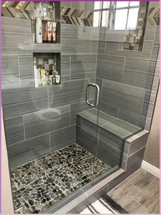 a walk in shower sitting next to a tiled floor and wall covered in gray tiles