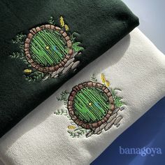 two towels with embroidered designs on them sitting next to each other, one green and the other white