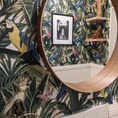 there is a mirror on the wall in this bathroom with tropical wallpaper and palm leaves