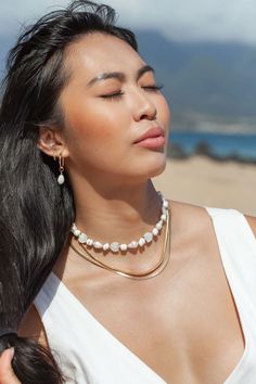 Flanked with luminescent natural white baroque pearls, puka shells, and carved mother of pearl, this unique luxurious pearl choker necklace evokes visions of Hawaii's white sands and soothing shores. Layer this with other shimmering beauties and you'll be ready for your tropical escape.✦ DETAILS ✦✧ Name: Keao (keh-AH-oh) - The light of the day.✧ Adjustable Necklace.✧ White Puka Shells.✧ Genuine Baroque Freshwater Pearls.✧ Carved Mother of Pearl Seashells.✧ 14kt Gold Filled with lobster clasp.✧ A Pearl Chain Shell Necklace, White Pearl Drop Choker Jewelry, Pearl White Baroque Pearl Choker, Elegant White Shell Choker Necklace, White Mother Of Pearl Jewelry With Pearl Chain, White Baroque Pearl Choker, White Pearl Charm Choker Jewelry, White Mother Of Pearl Necklace With Pearl Drop, White Baroque Pearl Shell Necklace