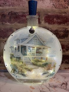 a glass bottle with a house painted on it