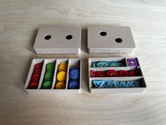 two white boxes filled with different colored dices on top of a wooden table next to each other