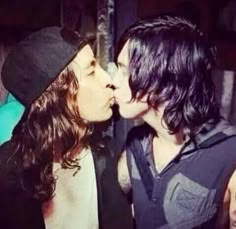 two people are kissing each other while one person is wearing a beanie and the other has long hair