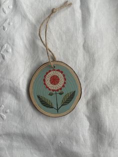 a wooden ornament with a flower painted on it's side hanging from a string