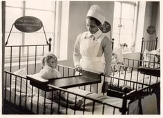 a woman standing next to two baby cribs in a room filled with beds