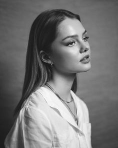 a black and white photo of a woman with long hair wearing a collared shirt