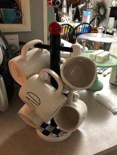 coffee mugs stacked on top of each other in front of a counter with various kitchen utensils