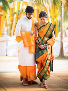 a man and woman dressed in orange and green sari standing next to each other