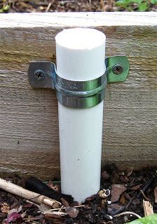 a close up of a metal object on the ground near wood and grass with leaves around it