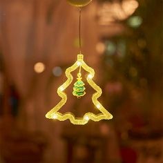 a lighted christmas tree ornament hanging from a string in front of a window