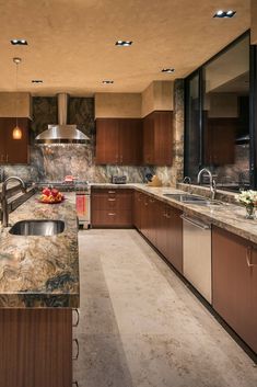 a large kitchen with marble counter tops and wooden cabinetry, along with stainless steel appliances