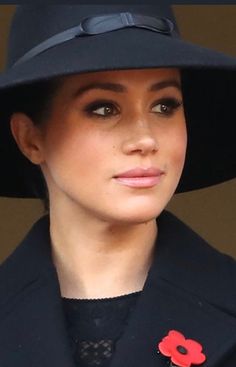 a close up of a person wearing a black hat with a red flower on it