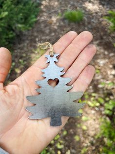 a hand holding a metal christmas tree ornament