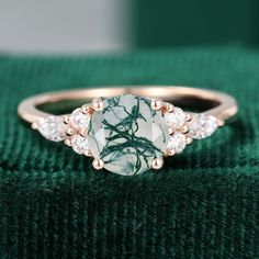 a green and white ring sitting on top of a green cloth with diamonds around it