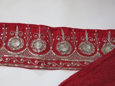 a red cloth with silver embroidered designs on it