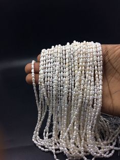 a hand is holding several strands of white beads