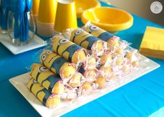 a table topped with yellow and blue desserts next to plates filled with cake pops