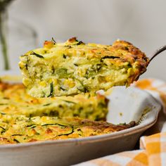 a piece of broccoli quiche being lifted from a casserole dish