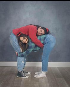 two women in jeans and red shirts are hugging each other