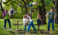 a group of young people standing around a park bench in the grass with trees behind them