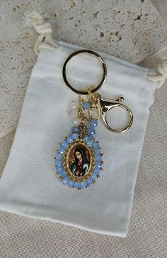 a keychain with an image of the virgin mary on it is sitting on a white cloth