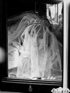 a woman in a veil and tiara looking out the window