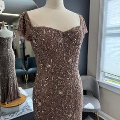 a dress on display in a room with two mannequins and one chair