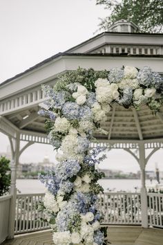 a white and blue floral arch in front of a gazebo