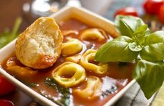 a bowl of soup with dumplings and basil