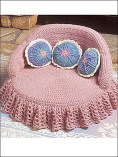 a pink crocheted bag with two blue buttons on it's top and bottom