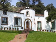 a white house sitting on top of a lush green field